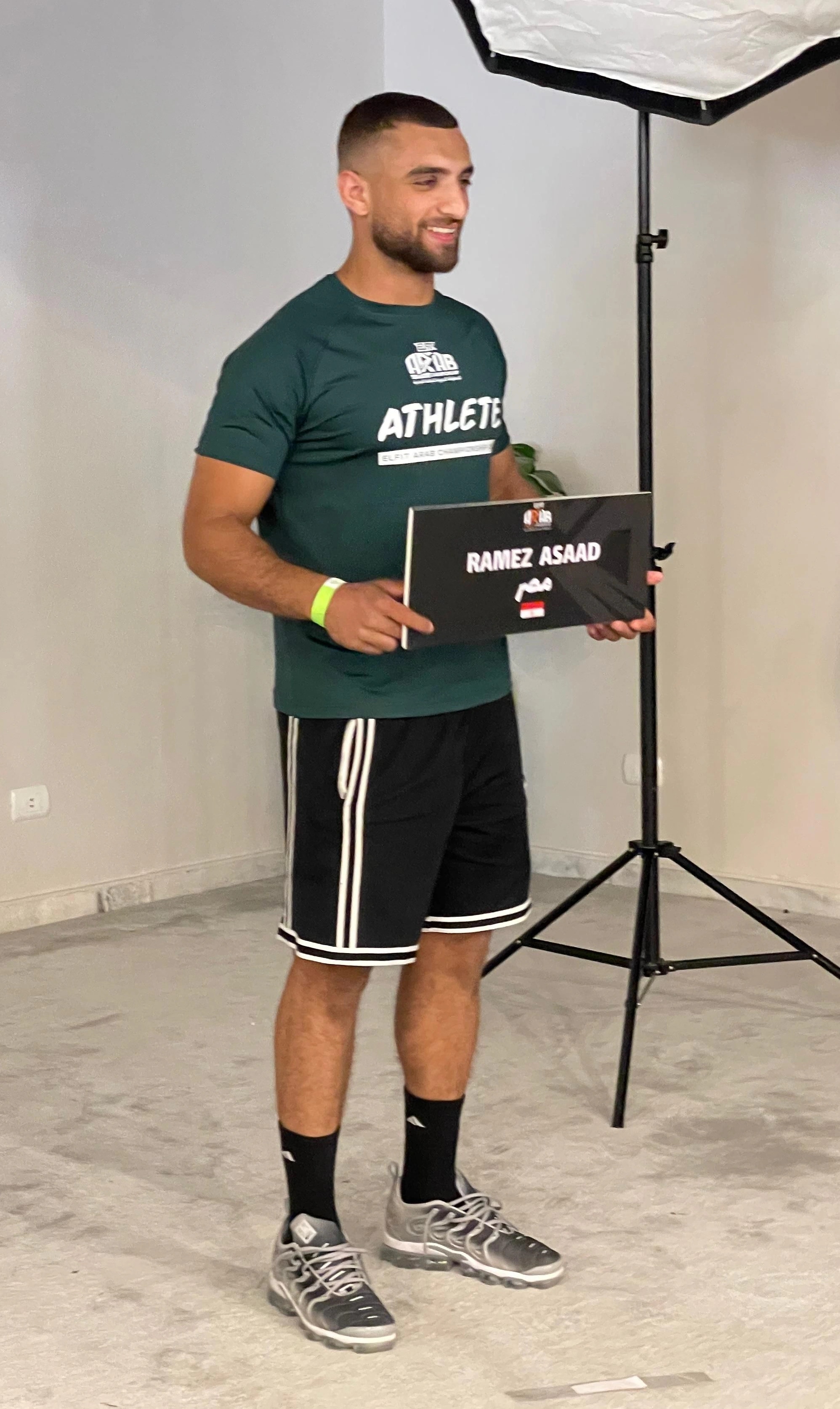 Ramez Asaad in an ELFIT Arab Championship athlete shirt, holding his name card with the Egyptian flag at the athlete photoshoot