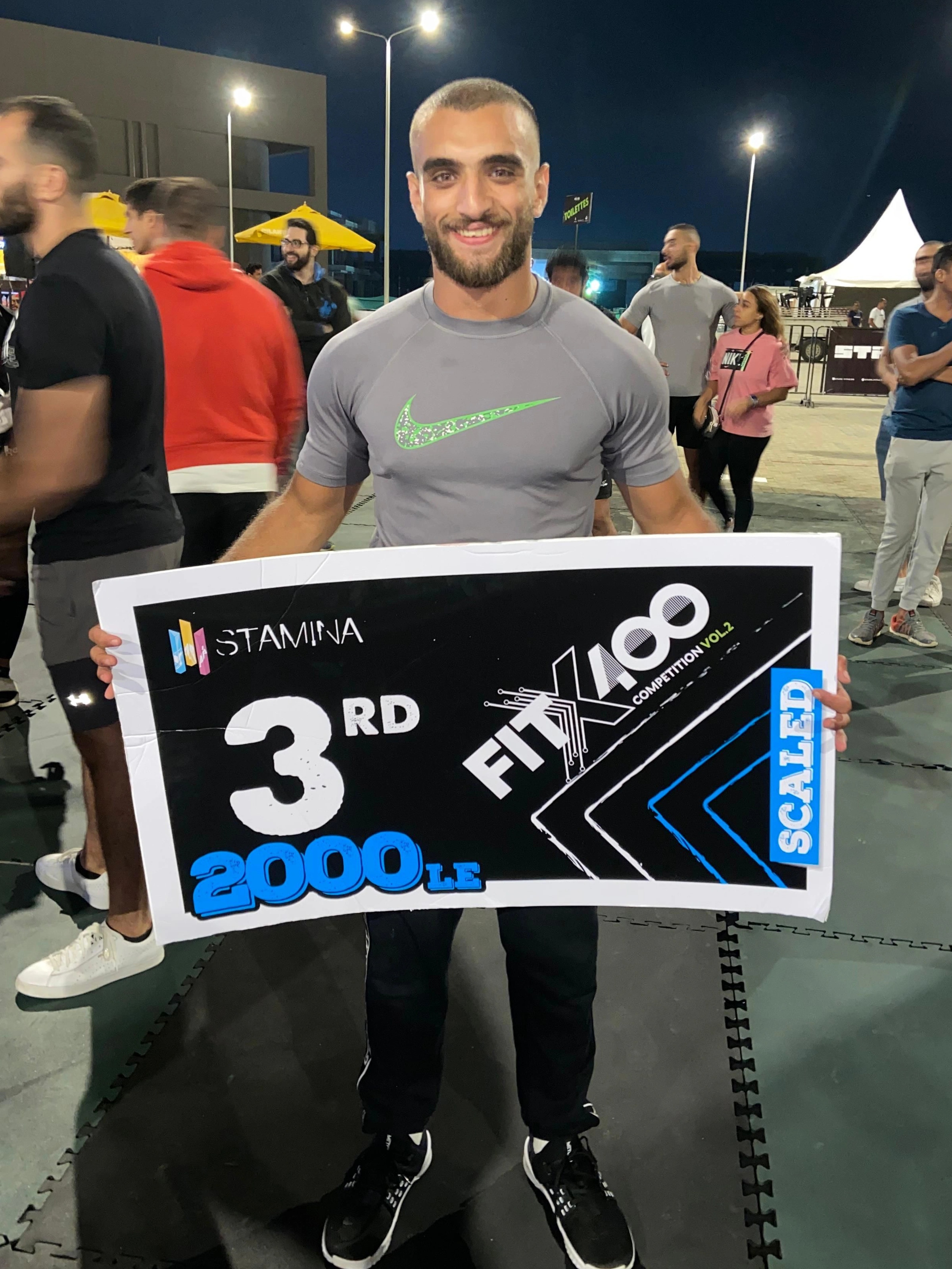 Ramez Asaad holding a third-place sign at FitX100
