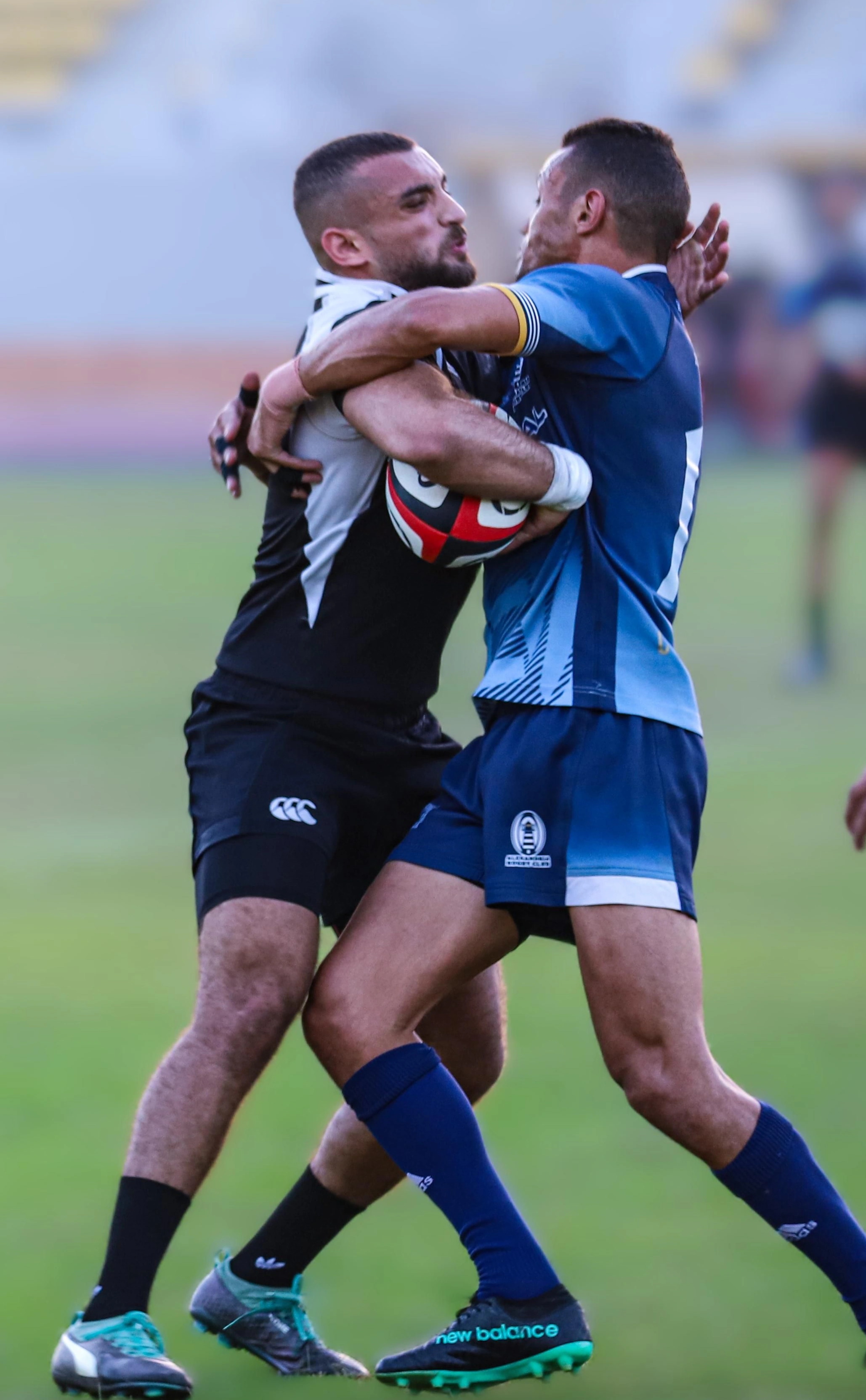 Ramez Asaad in a black jersey making a tackle in a rugby match