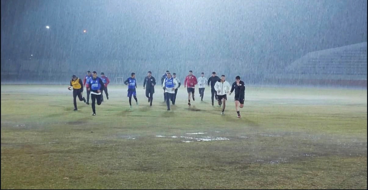 The Egypt national rugby squad running sprints across a flooded pitch in heavy rain