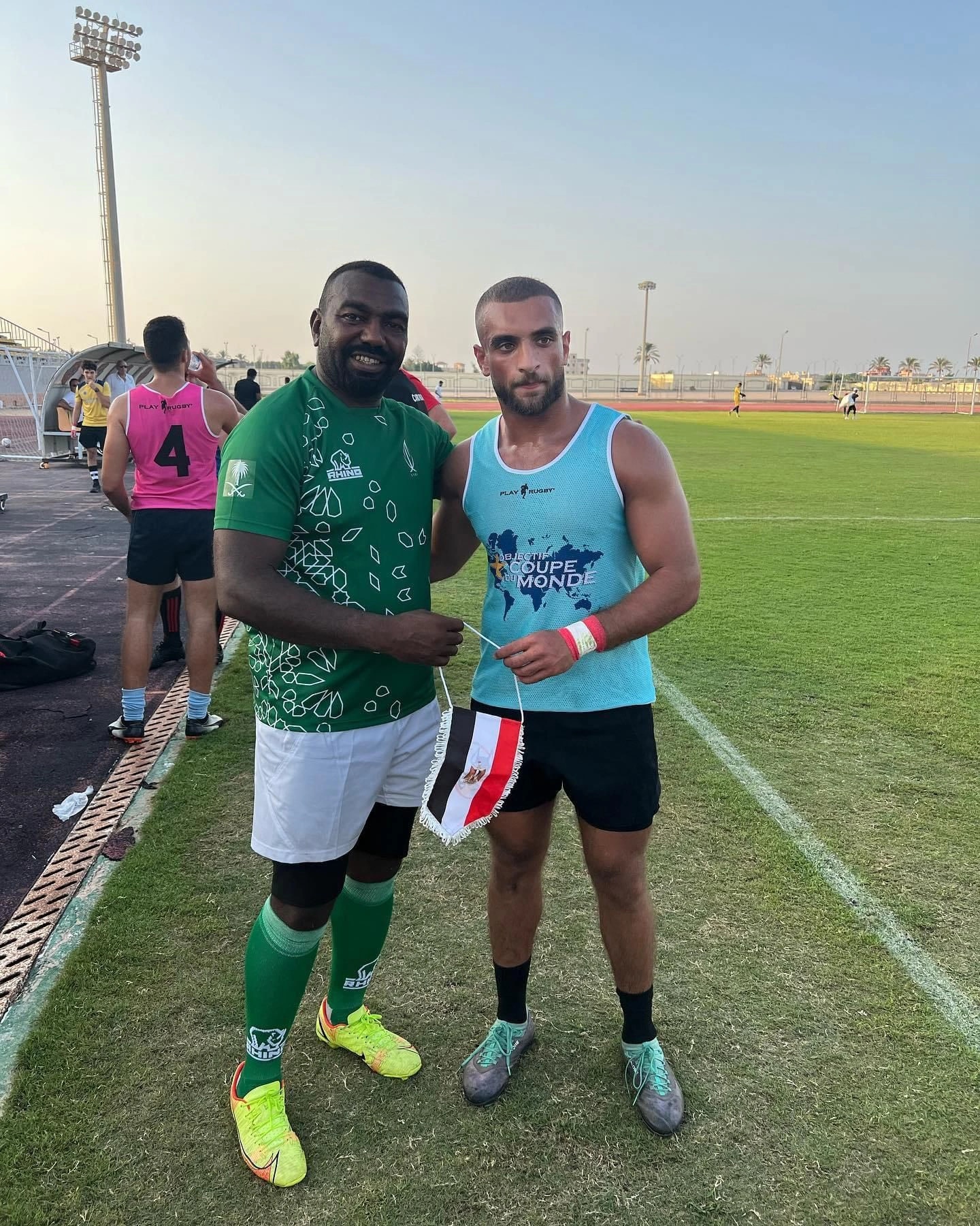Ramez Asaad in a training bib exchanging an Egyptian pennant with a Saudi Arabia rugby player on the pitch